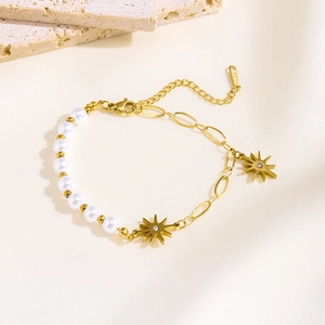Detail of baroque pearl and gold stainless steel chain bracelet with sun pendants