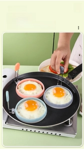 Tre anelli per uova in silicone colorati con manici per cuocere uova in una padella