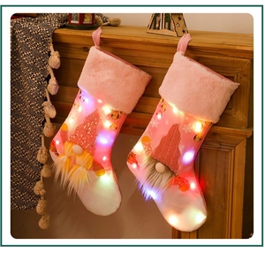 Dettaglio di calze natalizie rosa con luci LED e decorazioni di gnomi in peluche
