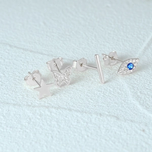 Macro shot of 925 sterling silver star, butterfly, and blue evil eye stud earring set