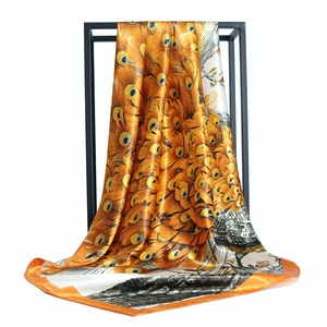 Elegant silk scarf featuring peacock feather print in vibrant orange and gold tones