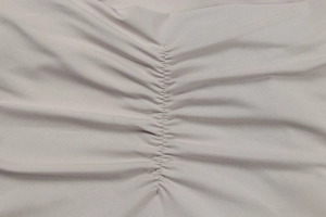 Detail of light grey ribbed knit fabric with elegant vertical ruching design for a slim fit