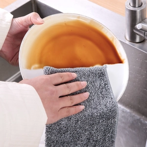 Thick bamboo fiber cleaning cloth wiping oil stains off a white ceramic plate in kitchen