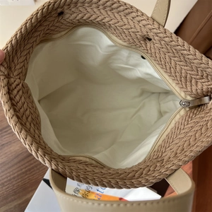 Detailed macro view showing the brown straw woven texture and secure zipper of the tote
