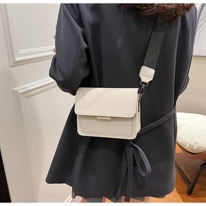 Detail of a beige PU leather crossbody bag featuring a wide fabric strap and fine stitching