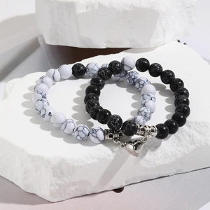 Close-up of marble beads and heart-shaped magnetic clasp on a white stone stand