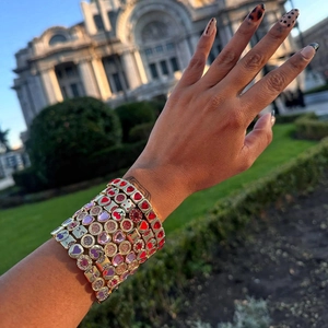Détail de bracelets superposés plaqués or 18 carats avec motifs de cœur et de cerise