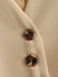 Detailed close-up of khaki twill fabric with premium tortoise-shell buttons and stitching