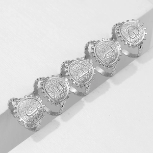 Silver stainless steel initial rings with hammered texture and beaded edges on white pedestals