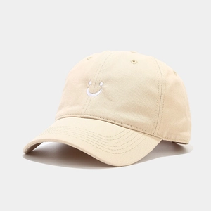 Detail of white smiley face embroidery on a beige cotton twill baseball cap