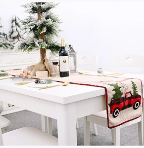 Detailed view of burlap Christmas table runner with red truck and pine tree pattern