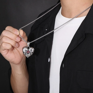 Detail of a punk style silver heart skull pendant with a red gemstone on a box chain