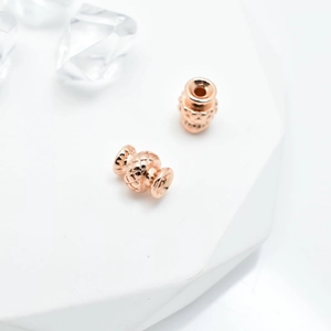 Rose gold quilted texture spacer beads for DIY jewelry making on white stone base