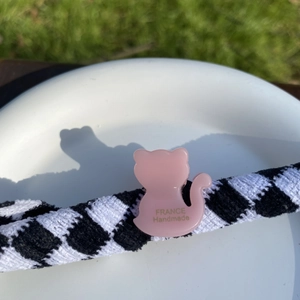 Macro d'une pince à cheveux chat en acétate rose et d'un bandeau à damier sur une assiette