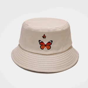 Détails de la broderie papillon sur un chapeau bob en coton beige aux coutures nettes