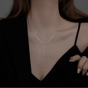 Dettaglio ravvicinato di una collana a nappa a forma di Y in argento su modella