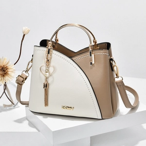 Chic cream and brown contrast handbag with metal ring handle on a white display stand