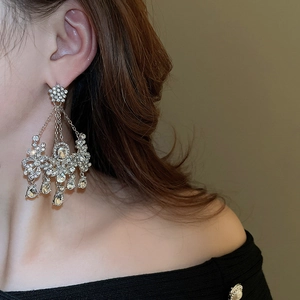 Gros plan de boucles d'oreilles pendantes argentées avec cristaux brillants sur un mannequin