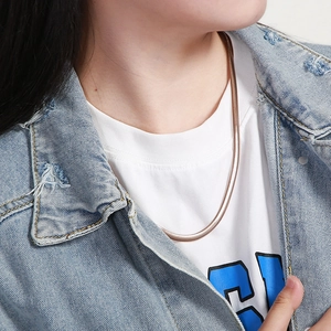 Close-up of stylish rose gold flat snake chain necklace worn by a female model