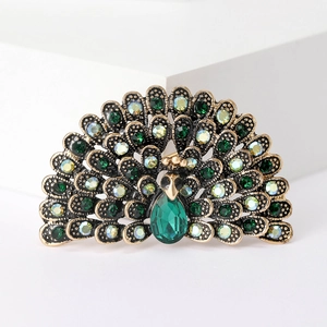 Detailed close-up of a vintage gold peacock brooch with sparkling green rhinestones