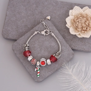 Detail of Christmas beaded bracelet with red charms and candy cane on silver snake chain