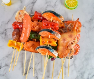 Spiedini di barbecue artificiali realistici con ali di pollo e gamberetti su rack in metallo