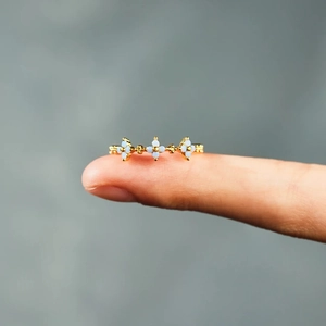 Macro detail of gold S925 silver ring featuring three delicate light blue flowers on finger