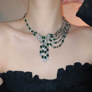 Close-up of luxury silver bow necklace with emerald crystals and cascading tassels
