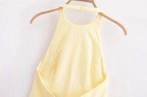 Detail of light yellow halter neck top with button closure on high-quality fabric