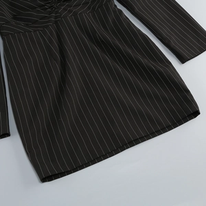 Detail of black striped V-neck dress showing fabric texture and cinched waistline