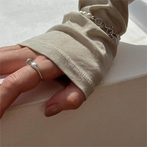 Close-up of minimalist 925 silver teardrop ring and elegant white pearl bracelet