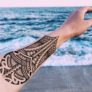 Waterproof black tribal wolf totem tattoo sticker applied on arm with beach background