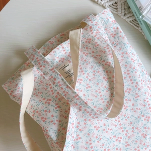 Detailed close-up of floral cotton tote bag texture and white canvas strap on wooden desk