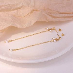 Elegant S925 sterling silver gold chain earrings with pearls on a white ceramic plate
