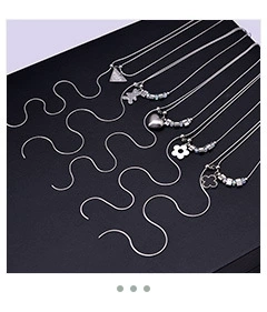 Detailed view of silver snake chains with diverse charms like heart, bear and clover