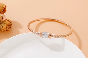 Détail d'un bracelet jonc en or rose avec cylindre serti de zircons sur plat céramique