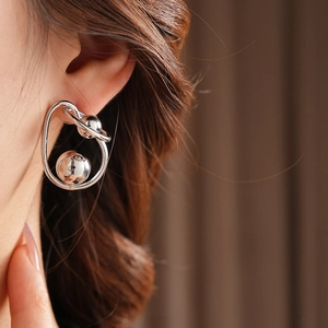 Close-up of a silver twisted ring and ball stud earring worn on a model's ear
