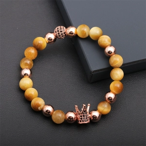 Detail of tiger eye beads bracelet with a crown charm and rose gold accents