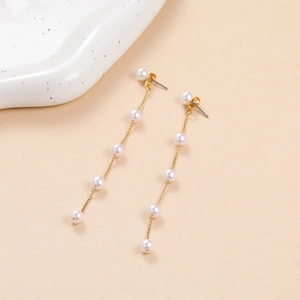 Detail of long pearl tassel earrings featuring gold chains and six round white pearls