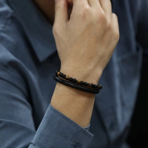 Detail of red tiger eye beads and woven leather bracelet set worn on a male wrist