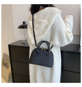 Detail showing the black chevron quilted leather texture and gold hardware on the handbag
