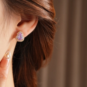 Close-up of a gold-plated gourd earring with purple stone and sparkling crystals