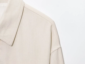 Détail de la couture haute densité et de la texture du lin mélangé sur l'épaule
