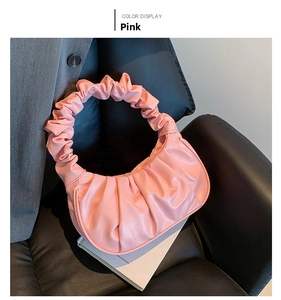 Detailed view of a pink pleated moon bag with cloud-handle on a black leather chair