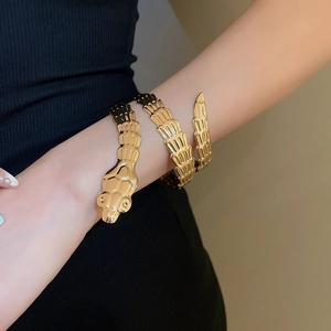 Detail of gold snake-shaped wrap bracelet featuring intricate scale texture on the metal
