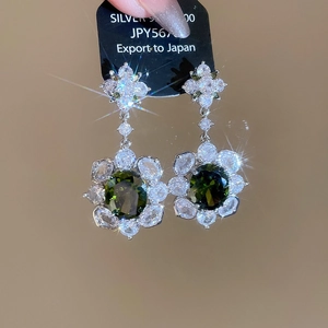 Detailed close-up of S925 silver drop earrings with oval green zircon and floral accents
