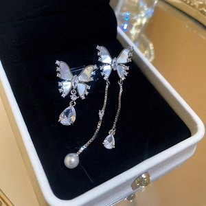 Close-up of asymmetric butterfly earrings with shell wings, zirconia, and pearl fringe