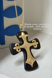 Detailed macro view of an ebony wood cross pendant with golden lily ornaments and chain