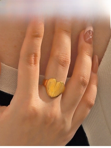 Detailed view of a gold heart-shaped ring with unique vertical stripes on model finger