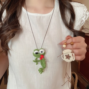 Detail of handmade crochet green frog pendant with star charm and wooden beads on model